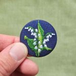 Petite broche brodée deux brins de muguet sur fond bleu marine porte-bonheur chance